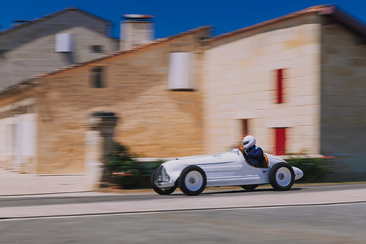 Voiture de course ancienne devant un château