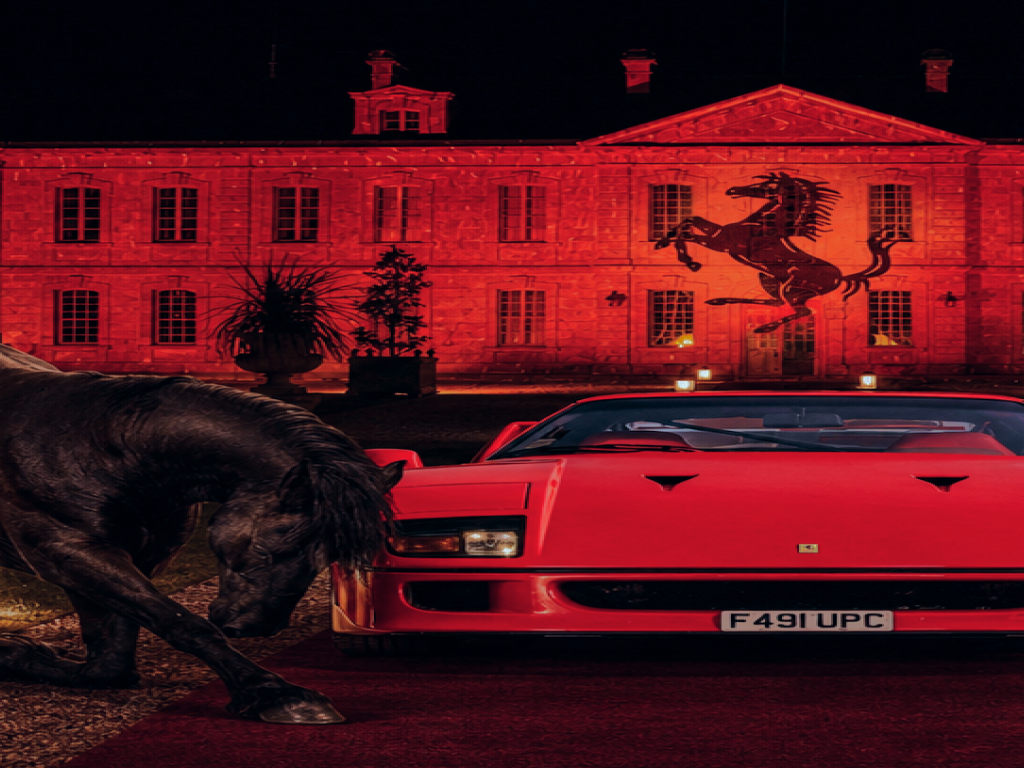 Ferrari rouge de nuit devant un château illuminé